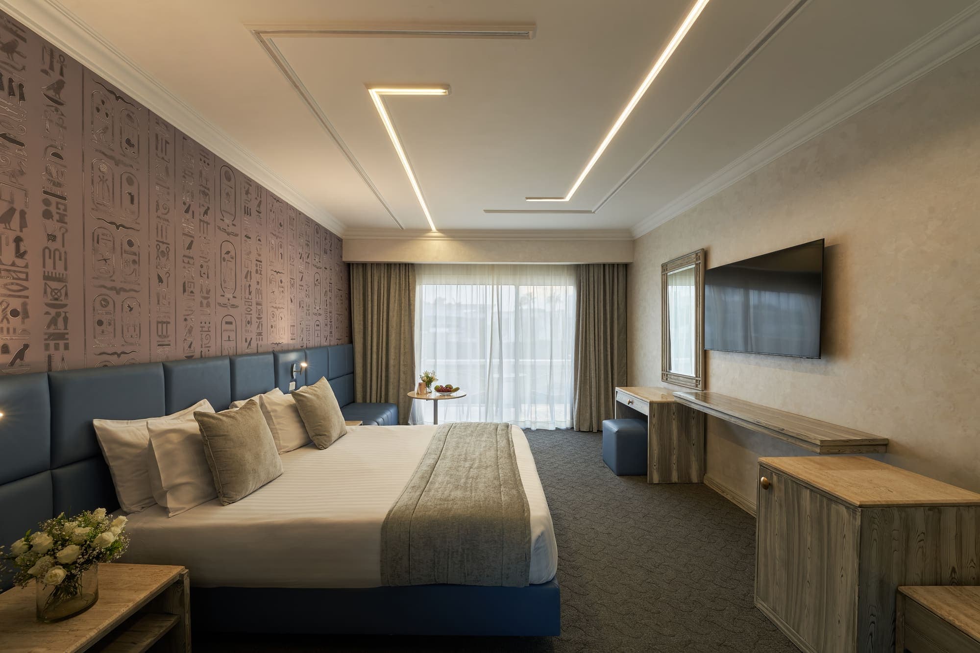 A deluxe double room with a blue headboard wall and balcony