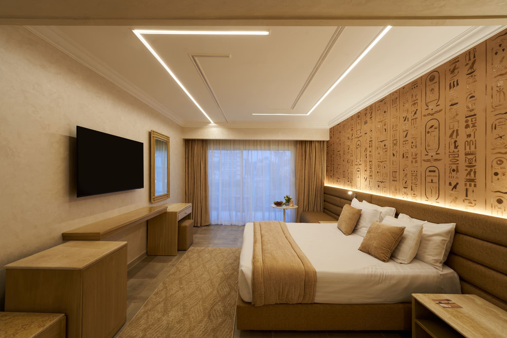 A deluxe double room with a hieroglyph-panelled headboard wall